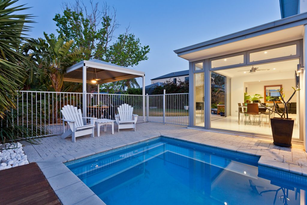 Une piscine devant une maison contemporaine avec un bassin géométrique