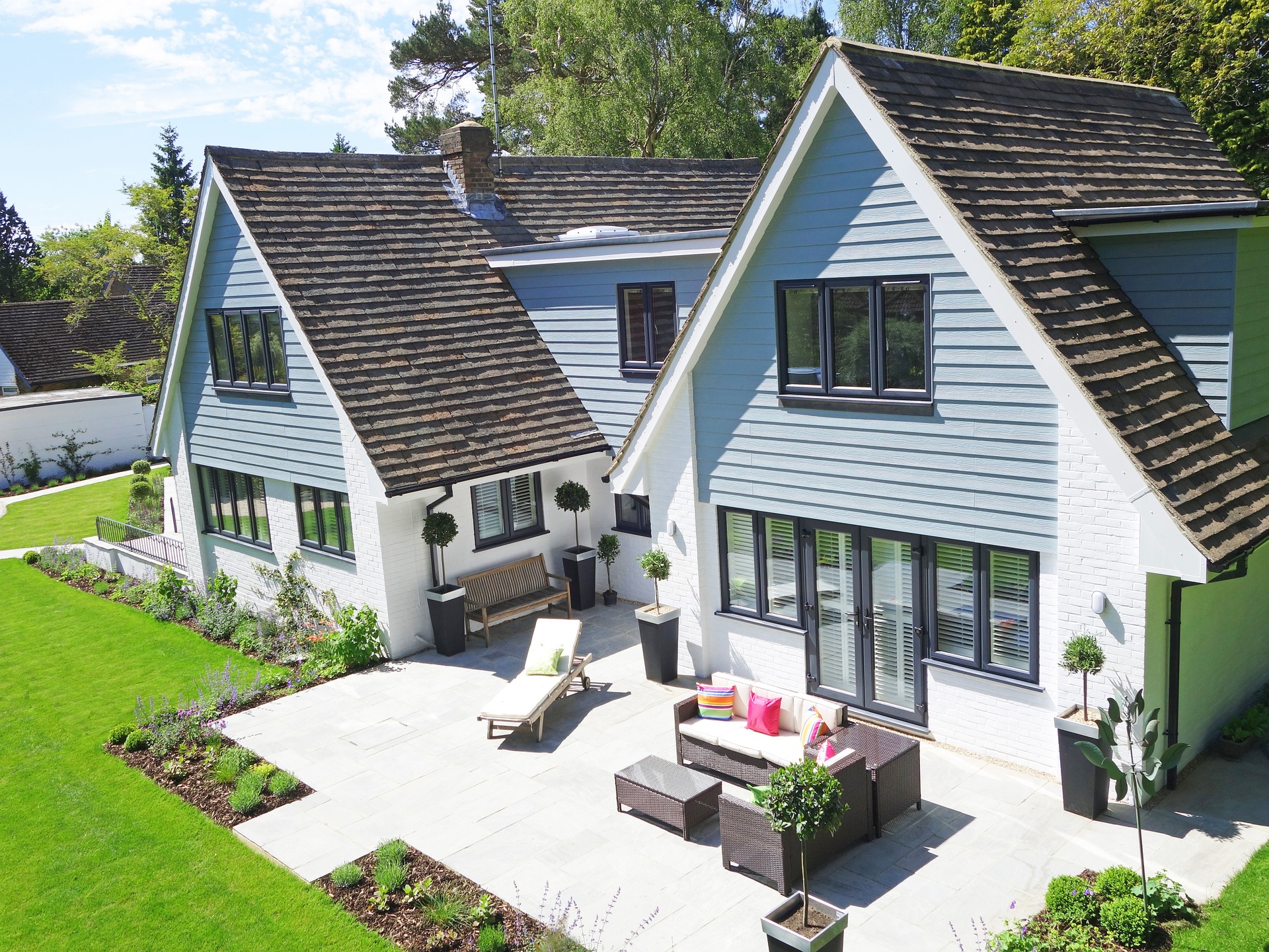 Une maison bleue avec une belle terrasse et un jardin