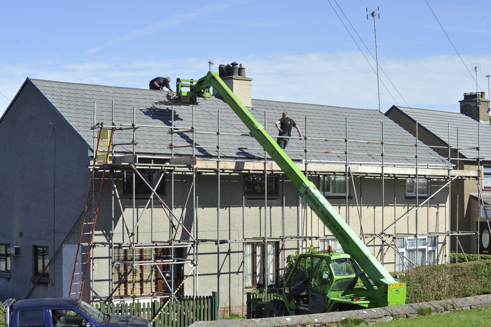 Travaux toit maison avec grue verte