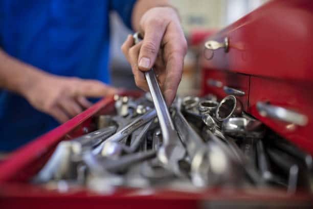 Artisan qui prend un clé dans sa boîte à outils pour un dépannage d'urgence