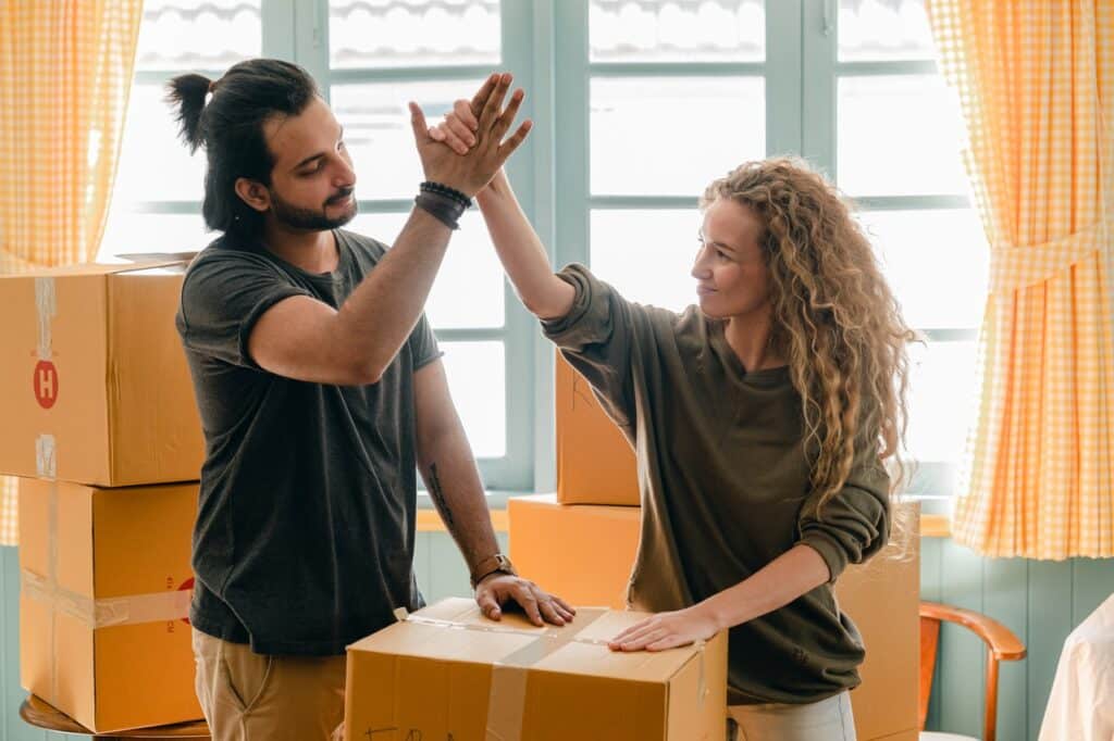 deux personnes au milieu de cartons qui se tapent dans la main